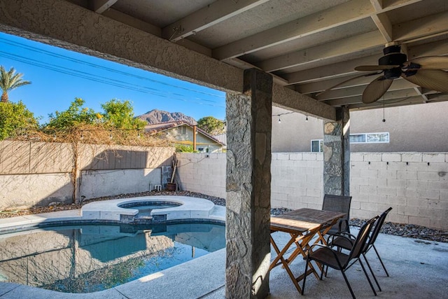 view of patio featuring ceiling fan, a swimming pool with hot tub, and a mountain view