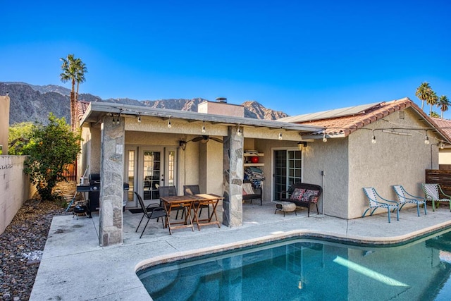 rear view of house featuring a patio, a mountain view, ceiling fan, and solar panels