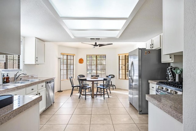 kitchen featuring white cabinetry, sink, light tile patterned floors, and stainless steel appliances