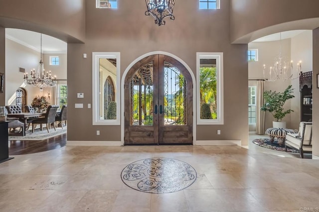 entryway featuring a towering ceiling, a notable chandelier, and french doors