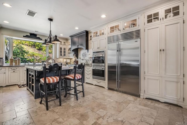 kitchen with a breakfast bar area, hanging light fixtures, a kitchen island, stainless steel appliances, and white cabinets