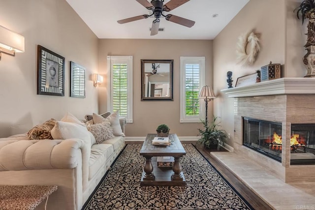 living room with a tile fireplace, wood-type flooring, and ceiling fan