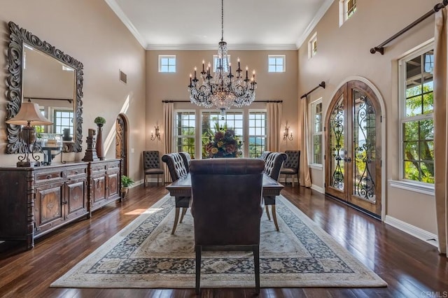 dining space featuring french doors, crown molding, an inviting chandelier, dark hardwood / wood-style floors, and a high ceiling