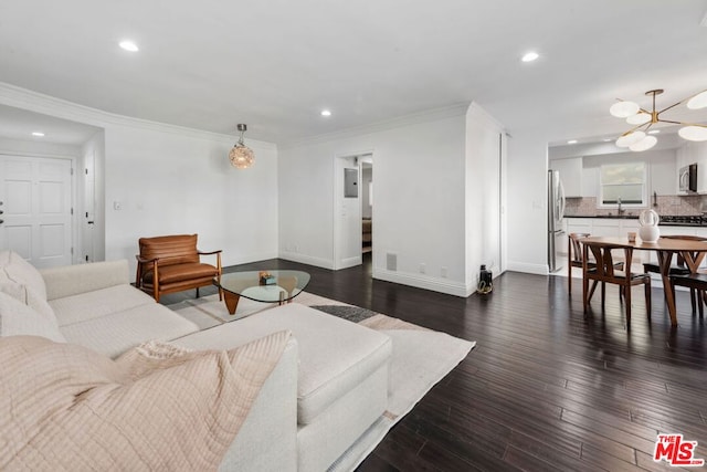 living room with sink, a notable chandelier, dark wood-type flooring, and ornamental molding