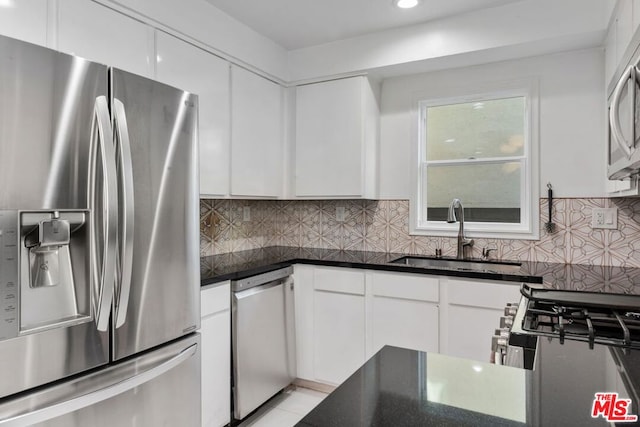 kitchen with tasteful backsplash, appliances with stainless steel finishes, sink, and white cabinets