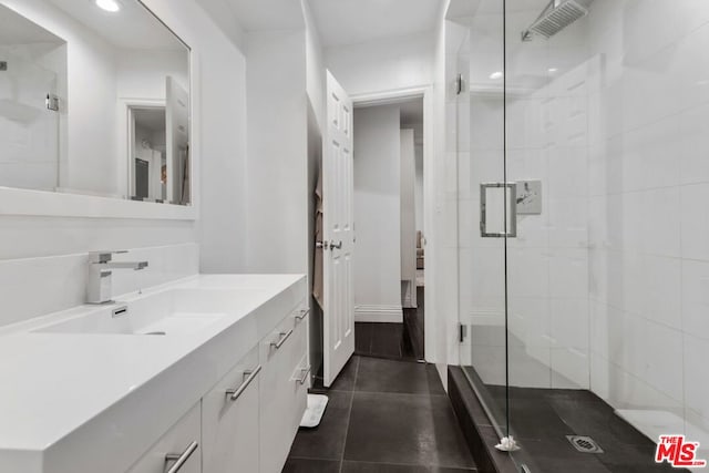 bathroom featuring a shower with door, vanity, and tile patterned floors