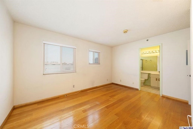 unfurnished bedroom featuring hardwood / wood-style floors and ensuite bath