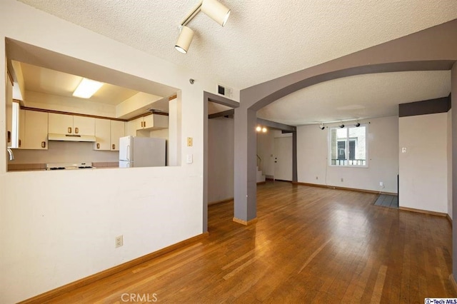 unfurnished living room featuring hardwood / wood-style flooring and a textured ceiling