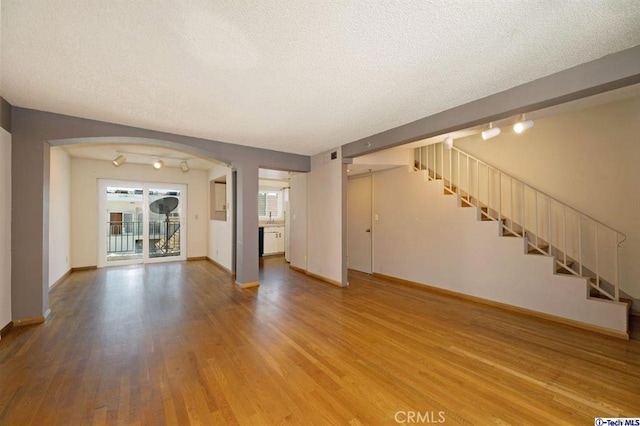 unfurnished living room with hardwood / wood-style flooring and a textured ceiling