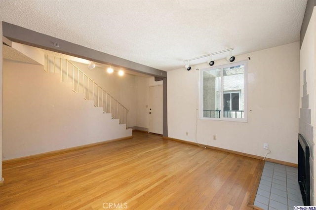 unfurnished living room with light hardwood / wood-style floors and a textured ceiling