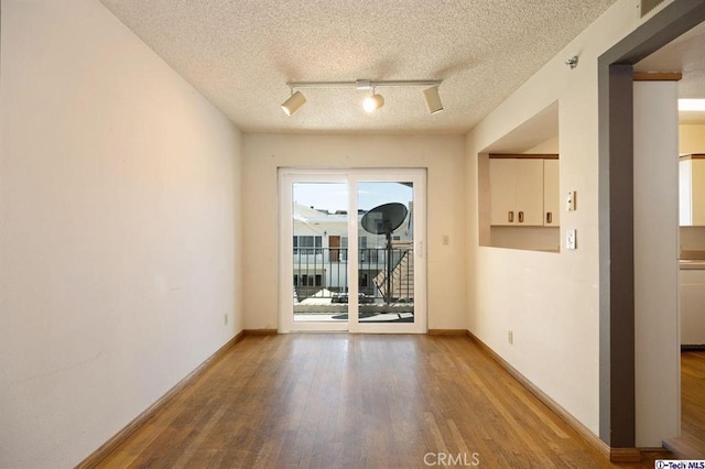 unfurnished room featuring wood-type flooring, track lighting, and a textured ceiling