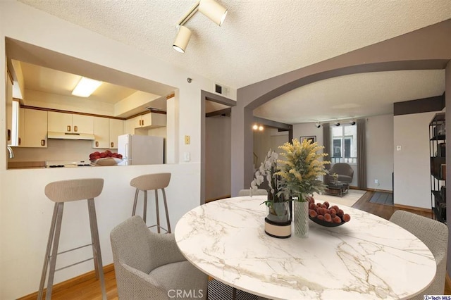 dining room featuring light hardwood / wood-style floors and a textured ceiling