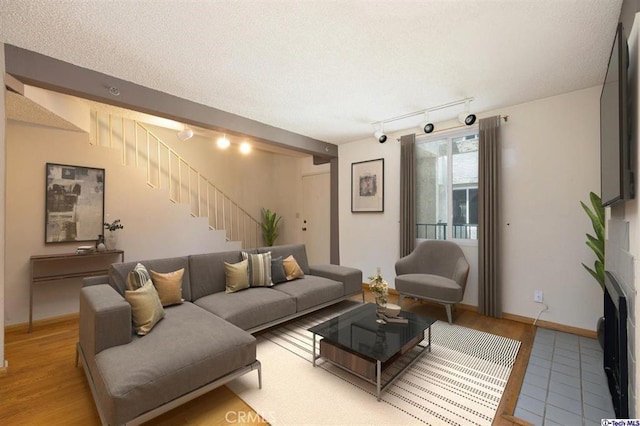 living room featuring rail lighting, a textured ceiling, and light wood-type flooring