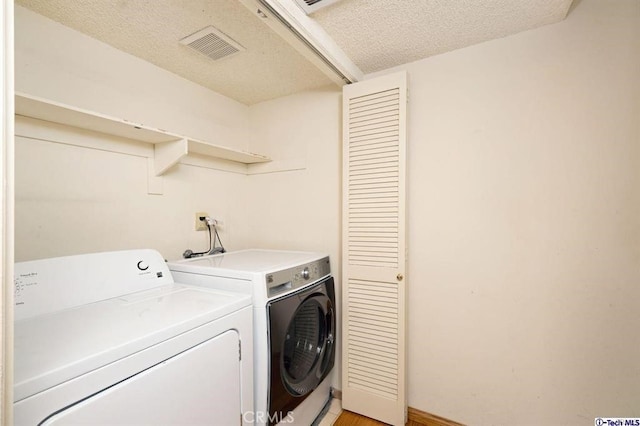 clothes washing area with a textured ceiling and independent washer and dryer