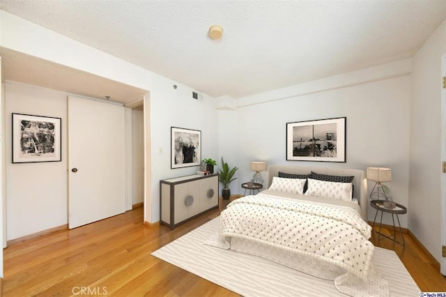 bedroom featuring a textured ceiling and light hardwood / wood-style floors