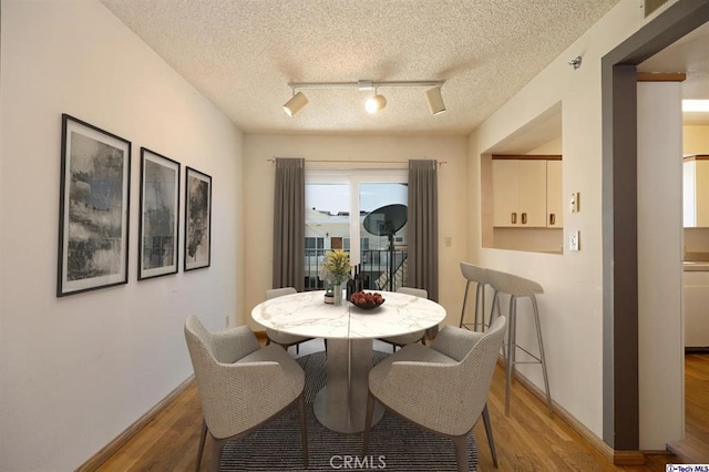 dining space featuring hardwood / wood-style floors, track lighting, and a textured ceiling