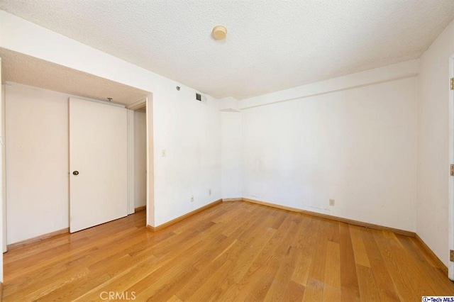 unfurnished bedroom with a textured ceiling and light wood-type flooring