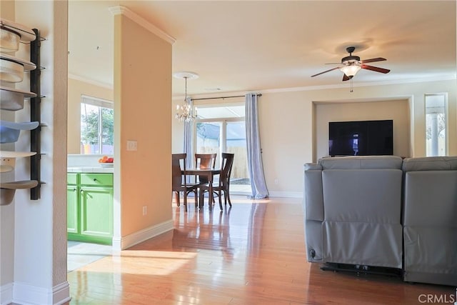 living room featuring crown molding, wood-type flooring, and ceiling fan with notable chandelier