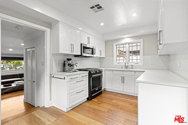 kitchen with white cabinetry, sink, black range with gas stovetop, and light wood-type flooring