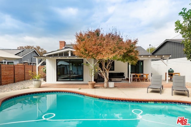 rear view of property featuring a fenced in pool, a patio area, and outdoor lounge area