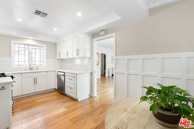 kitchen featuring sink, white cabinetry, light wood-type flooring, dishwasher, and decorative backsplash