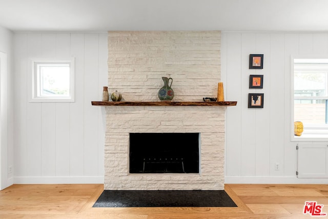 details with hardwood / wood-style flooring and a stone fireplace