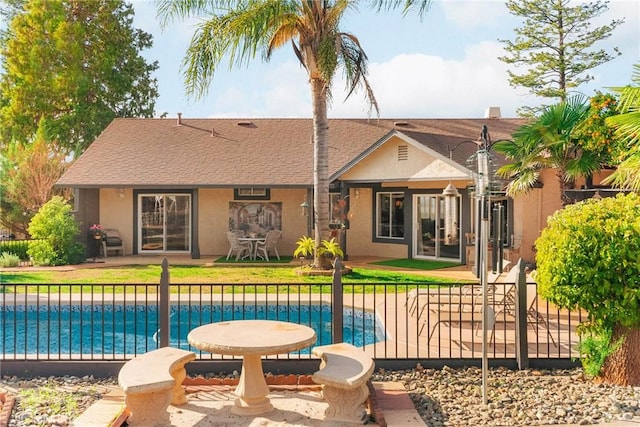 back of property featuring a fenced in pool and a patio