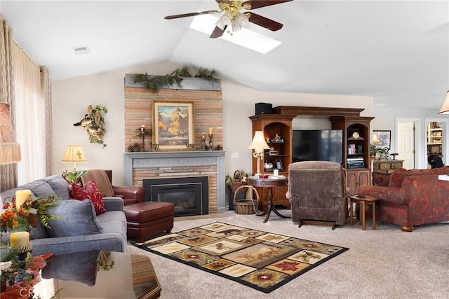 living room featuring ceiling fan, carpet floors, a stone fireplace, and vaulted ceiling