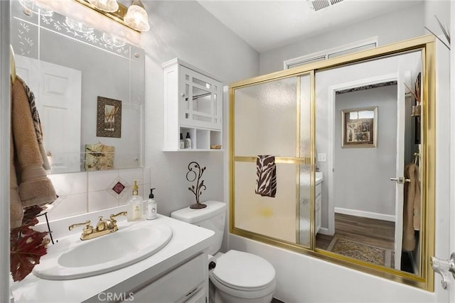 full bathroom with vanity, decorative backsplash, shower / bath combination with glass door, and toilet