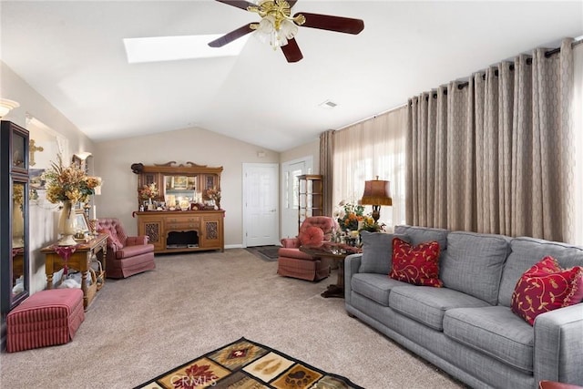 carpeted living room featuring vaulted ceiling with skylight and ceiling fan