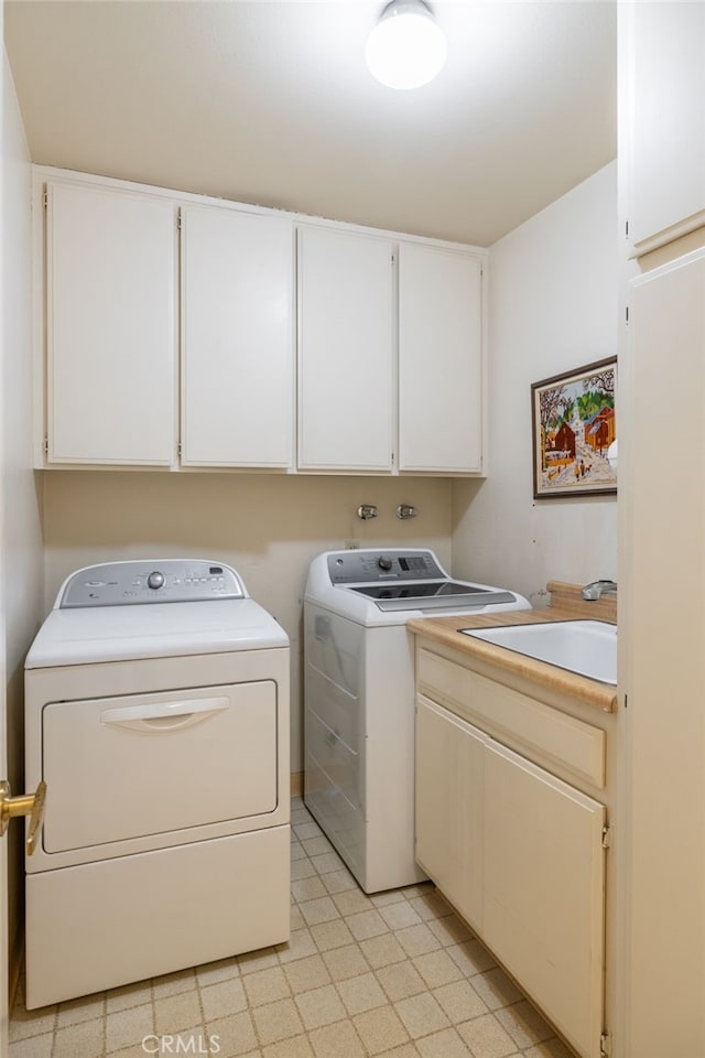 clothes washing area with sink, cabinets, and washing machine and clothes dryer