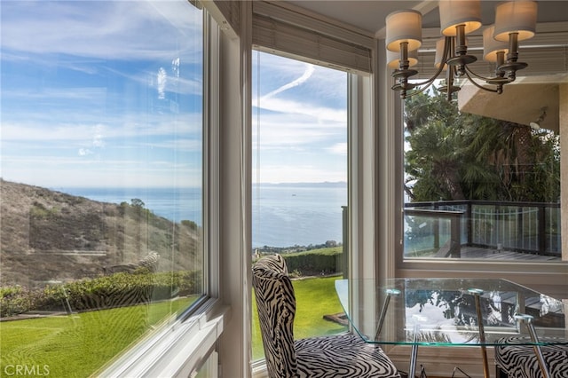 sunroom / solarium featuring a water view, a healthy amount of sunlight, and a notable chandelier