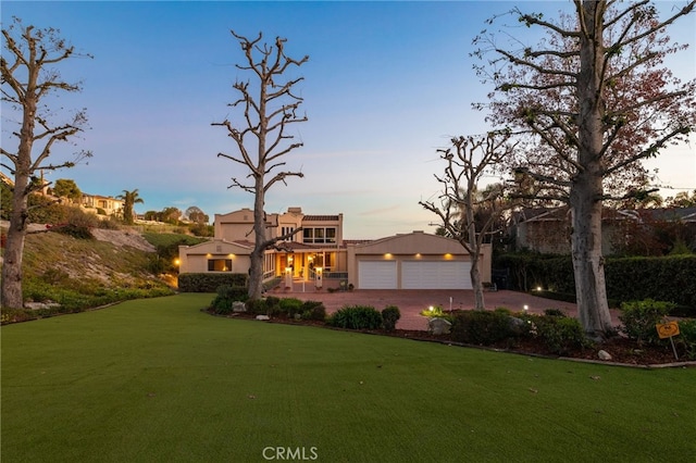 view of front of home with a garage, driveway, a front yard, and stucco siding