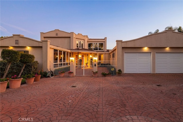 view of front of property featuring a garage, a gate, fence, and stucco siding