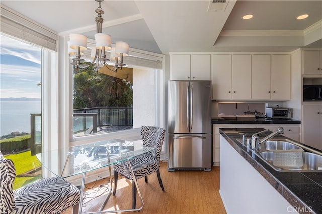 kitchen featuring stainless steel fridge, decorative light fixtures, sink, and white cabinets