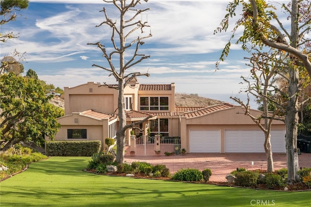 mediterranean / spanish home featuring a garage and a front yard