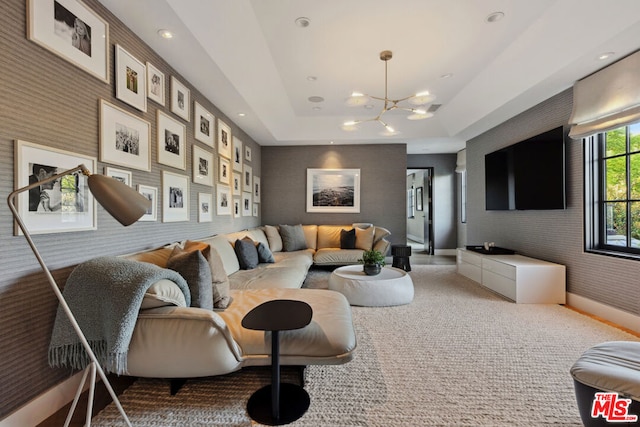 carpeted living room with an inviting chandelier and a tray ceiling