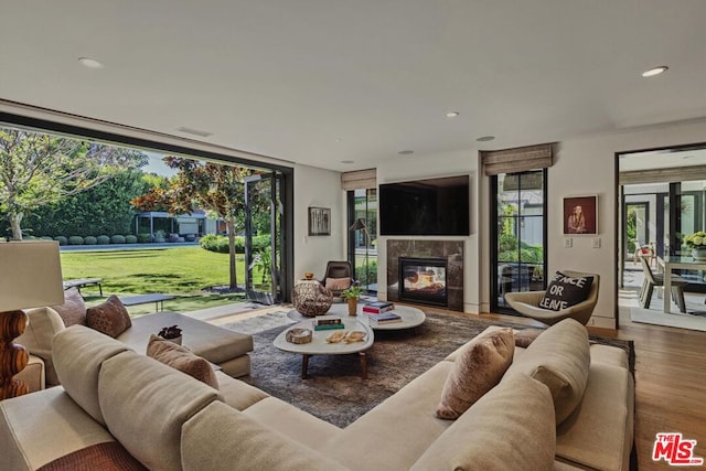 living room featuring a tiled fireplace, hardwood / wood-style flooring, plenty of natural light, and expansive windows