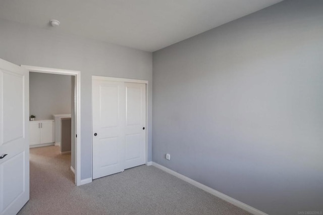 unfurnished bedroom with light colored carpet and a closet