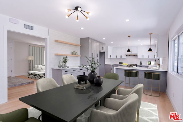 dining space with an inviting chandelier, sink, and light wood-type flooring