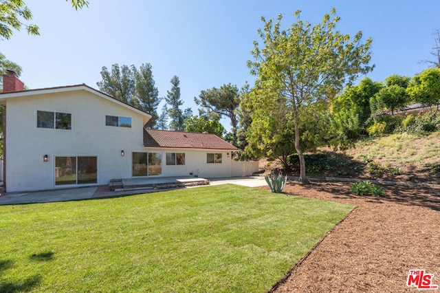 rear view of house with a yard and a patio