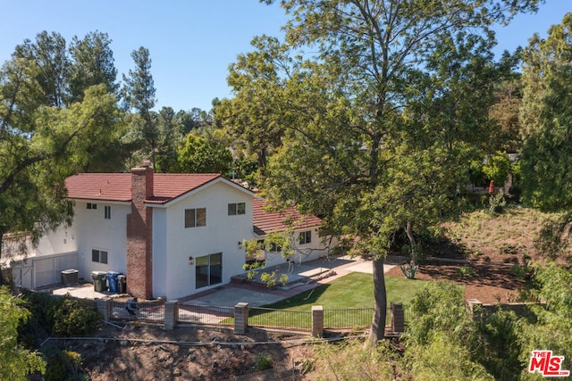 back of house featuring central AC unit, a patio area, and a lawn