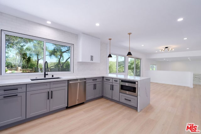 kitchen with sink, gray cabinets, appliances with stainless steel finishes, tasteful backsplash, and decorative light fixtures