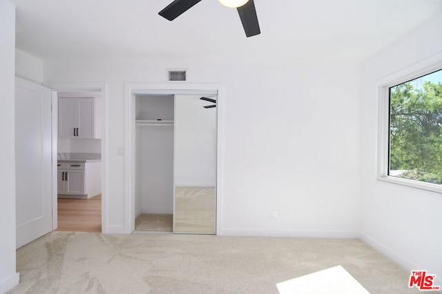 unfurnished bedroom with ceiling fan, light carpet, and multiple windows