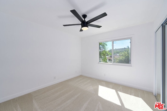 carpeted spare room with ceiling fan