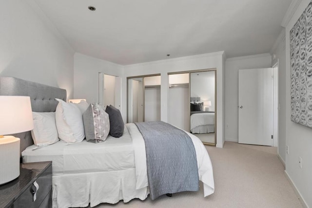 carpeted bedroom with ornamental molding and two closets