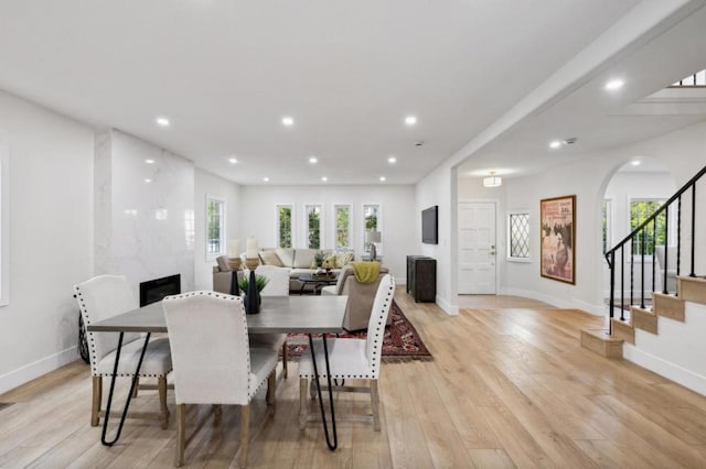 dining area with a healthy amount of sunlight, a large fireplace, and light wood-type flooring