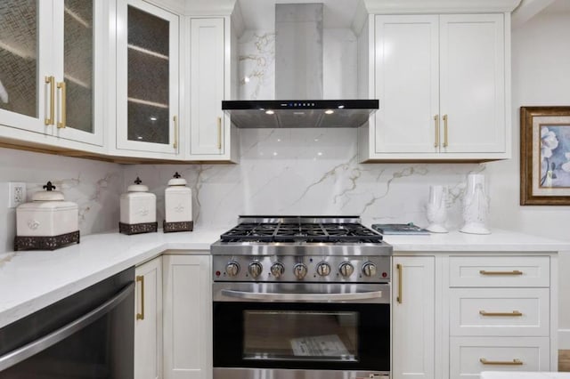 kitchen with stainless steel range with gas cooktop, dishwasher, wall chimney range hood, decorative backsplash, and white cabinets