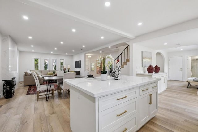 kitchen featuring light stone countertops, a center island, white cabinets, and light wood-type flooring