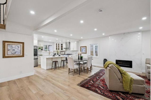 living room with beam ceiling, a high end fireplace, and light wood-type flooring